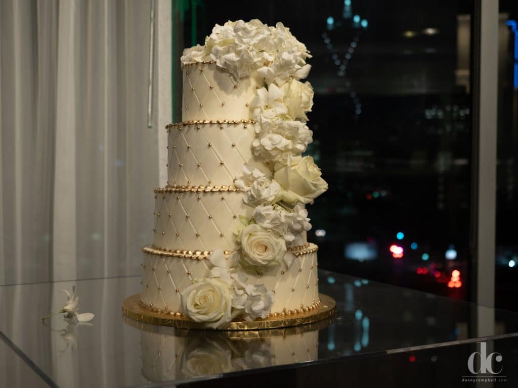 Four-tier wedding cake with cascading white flowers at our event space in Dallas, TX