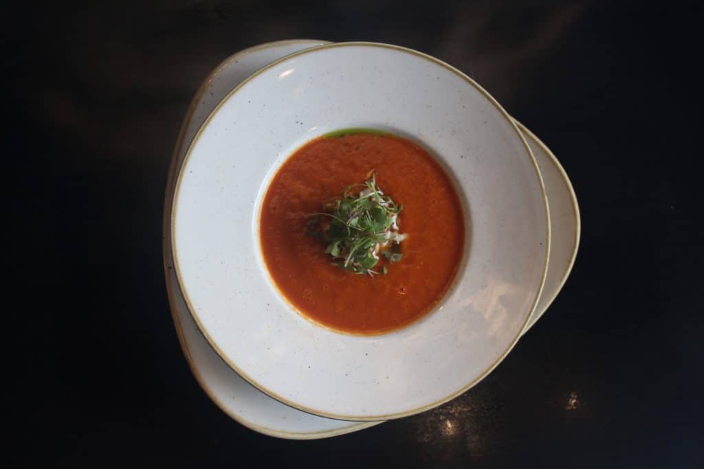 Top-down view of tomato soup with a garnish at our Dallas hotel